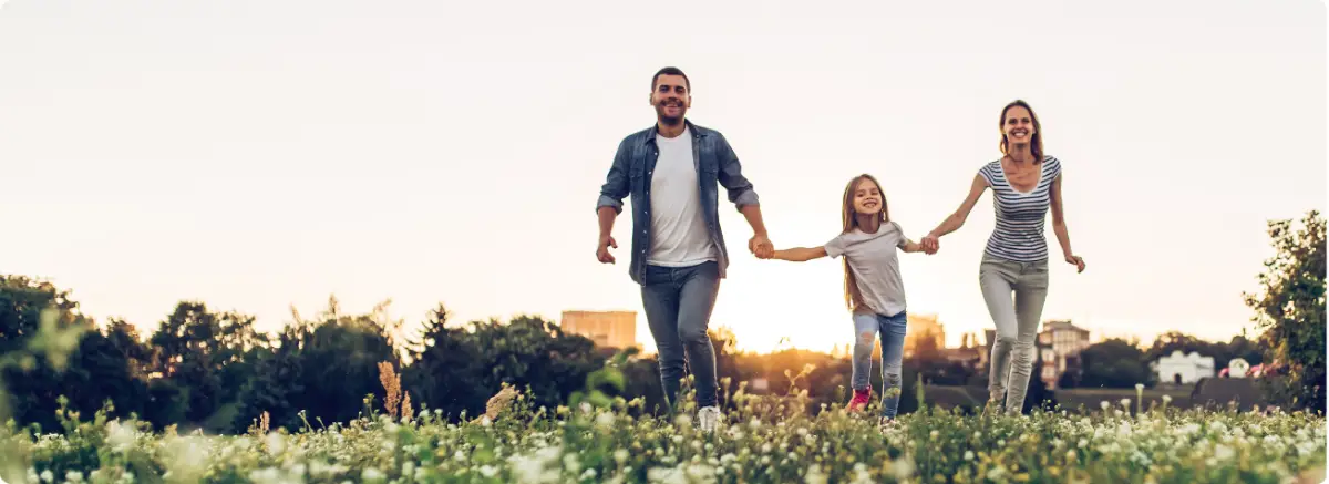 A happy family running together in a sunlit field, representing the successful integration of family healing